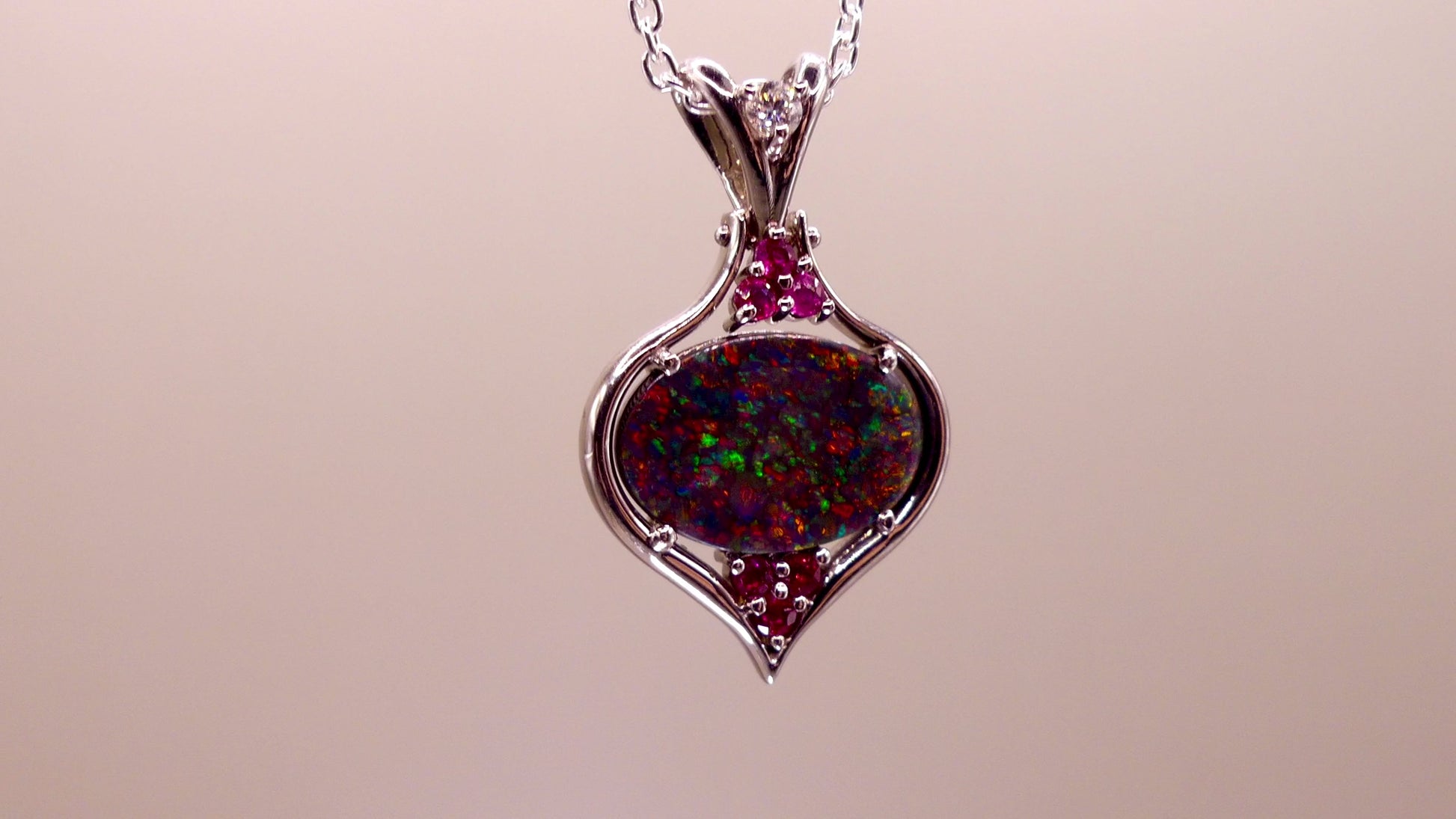 This stunning 18k white gold pendant features a rare and captivating Australian black opal accented with a brilliant center diamond and stunning rubies. Elevate your look with this breathtaking piece and indulge in the unique beauty and elegance of this precious gemstone.

Opal Weight- 1.6ct Australian Black Opal

Opal Origin- Lightning Ridge Australia

Setting- Rhodium Plated 18k White Gold

Accent Stones- Center Diamond, Rubies

Chain- 18k White Gold 45cm in length
