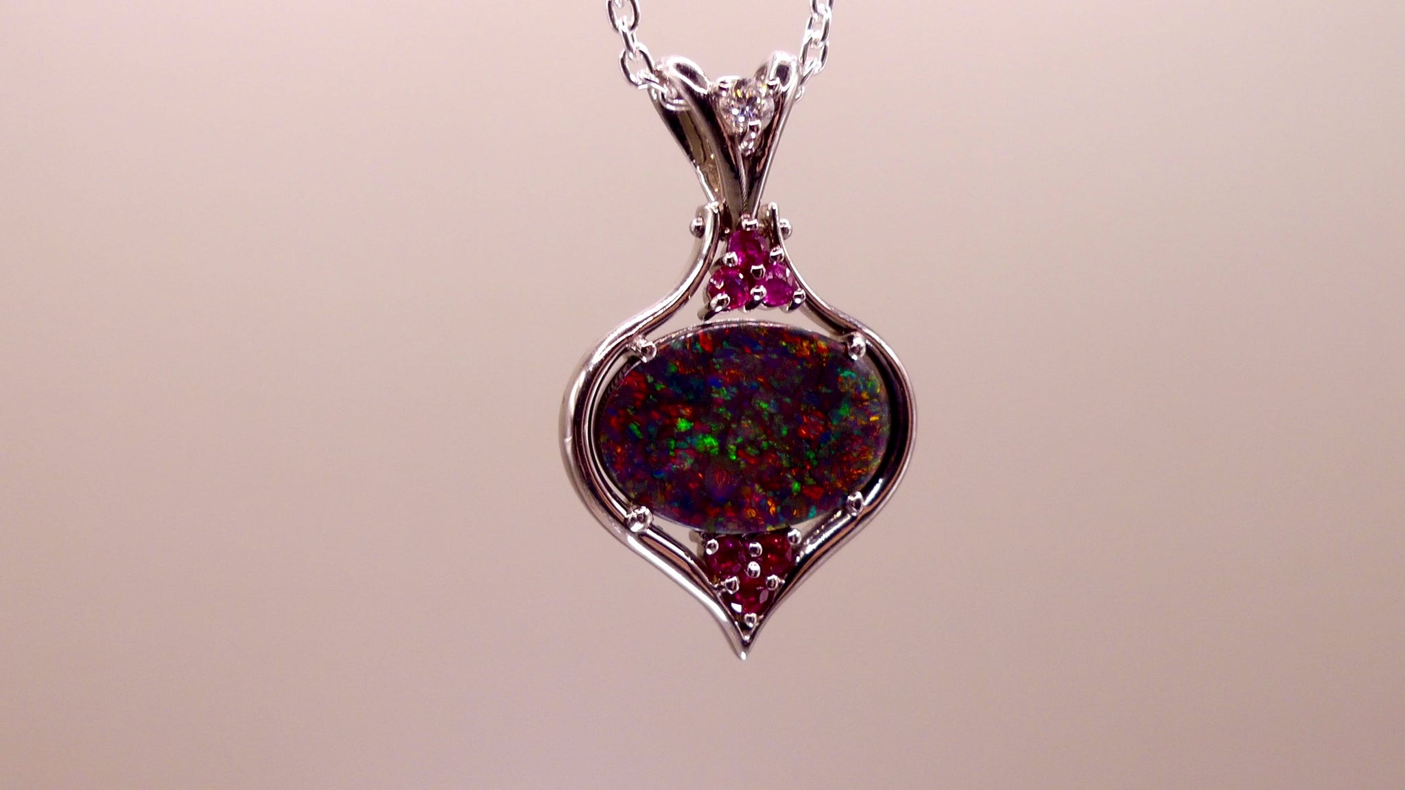 This stunning 18k white gold pendant features a rare and captivating Australian black opal accented with a brilliant center diamond and stunning rubies. Elevate your look with this breathtaking piece and indulge in the unique beauty and elegance of this precious gemstone.

Opal Weight- 1.6ct Australian Black Opal

Opal Origin- Lightning Ridge Australia

Setting- Rhodium Plated 18k White Gold

Accent Stones- Center Diamond, Rubies

Chain- 18k White Gold 45cm in length
