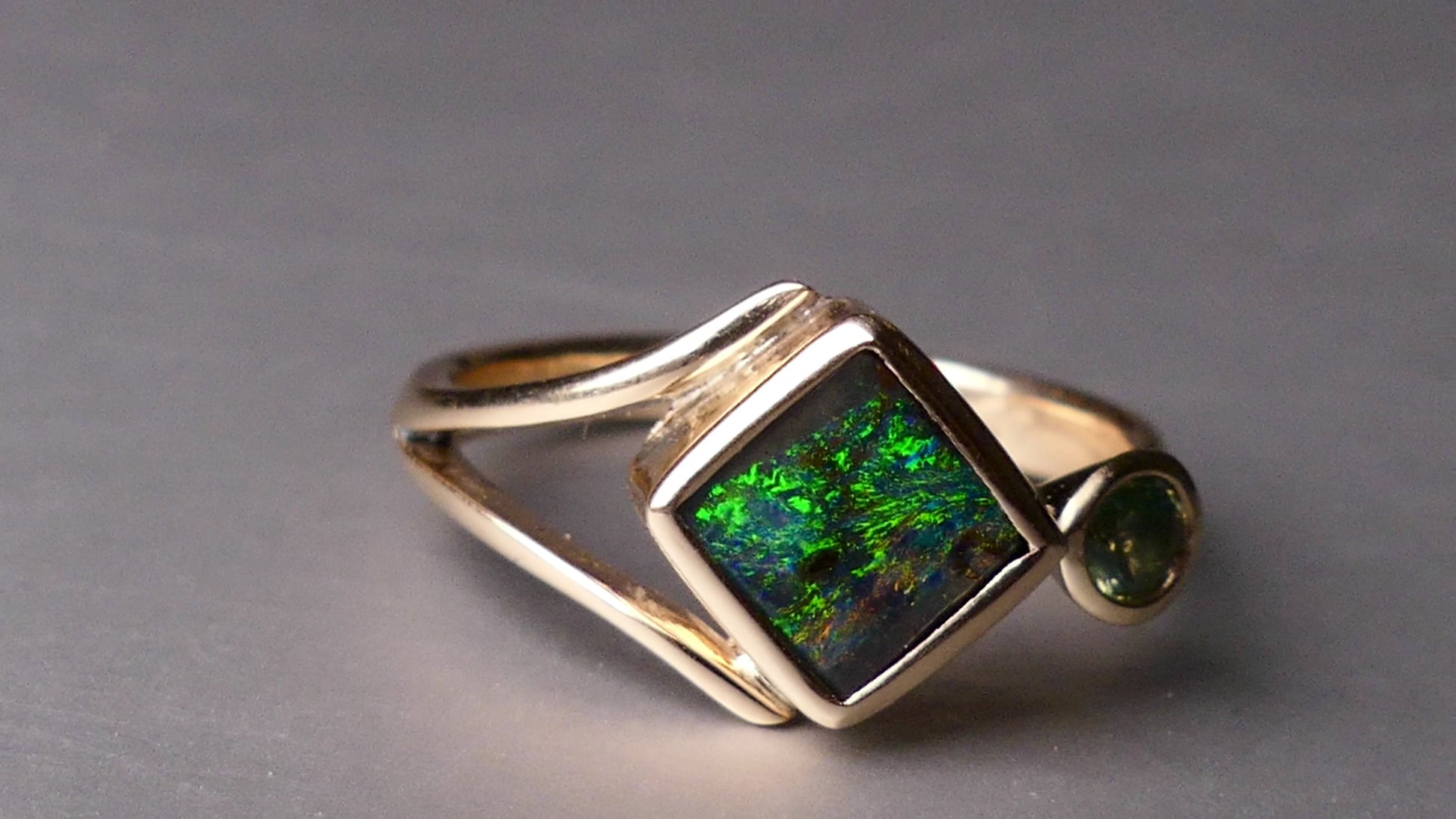 Discover the elegance of this unique 9k gold Australian Boulder Opal ring, beautifully paired with a stunning Australian sapphire. The vibrant opal’s natural patterns and the sapphire’s green blue hues create a captivating contrast, making this ring a true statement piece.